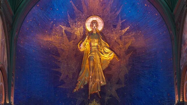 Golden religious statue stands in cathedral altar, glowing serene inside ornate church interior with arches and mosaics. Golden figure remains centered above nave in rich blue wall.