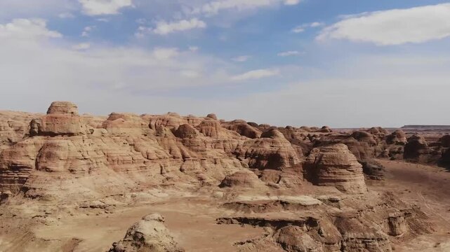 Aerial drone view of Xinjiang Devil City yardang landforms under blue sky with scattered clouds