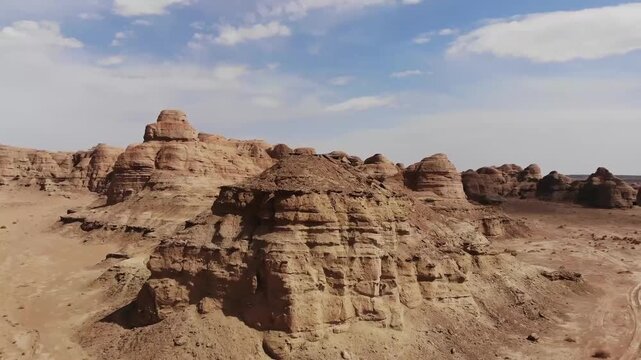 Aerial drone view of Yardang landforms in the Gobi Desert, Xinjiang, China &ndash; eroded sedimentary rock formations under blue sky with scattered clouds
