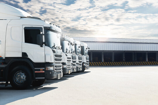 Row of Semi Trucks on The Parking Lot at Warehouse. Freight Transportation Logistics. Shipping Cargo Container, Warehouse Port. Distribution Warehouse. Economy Business Transportation.	
