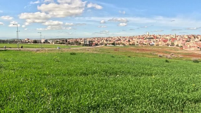 Rural landscape of Tahla in northern Morocco, featuring green farmland, rolling hills and expanding town buildings, reflecting agricultural life and a calm countryside atmosphere