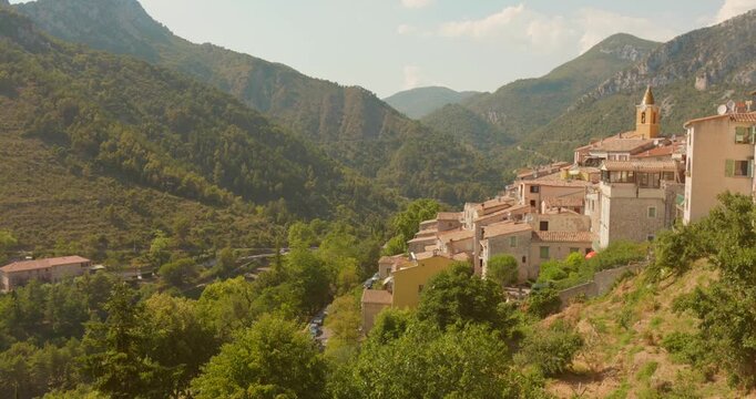 Hillside shot of Sainte-Agn&egrave;s, one of France's most beautiful villages, with stone buildings and church tower rising from forested mountain slopes. Ideal for travel and heritage content.