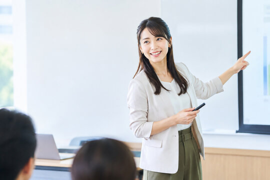 教室でプレゼンをする笑顔の日本人女性教師