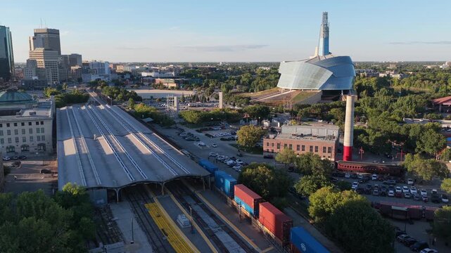 Freight train entering Union Station, Winnipeg at the Forks. Winnipeg skyline visible, panoramic drone view.