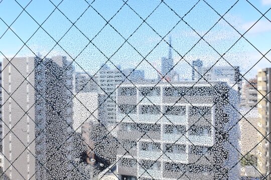 網入りガラスの結露と窓から見えるビル群