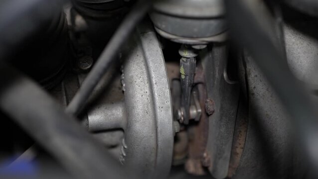 A close-up view shows a car engine turbocharger housing with its actuator rod arm link mechanism under the hood.
