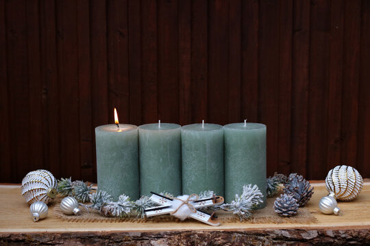 Modern country-style Christmas decor for the first Sunday of Advent, featuring sage-green candles on rustic wood and space for text.