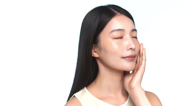 頬に手を当てて肌のケアをする若い日本人女性のビューティーカット（白背景）