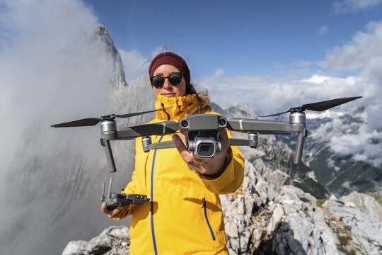 Young woman holding a drone with camera, DJI Mavic Pro, Wetterstein Mountains, Garmisch Partenkirchen, Bavaria, Germany