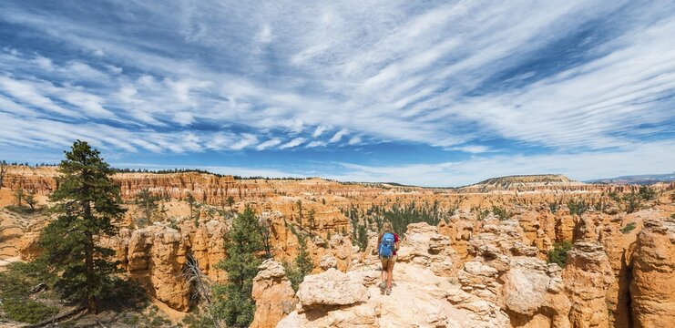 Hiker with backpack in bizarre landscape, reddish rocky landscape with fairy chimneys, sandstone formations, Bryce Canyon National Park, Utah, USA
