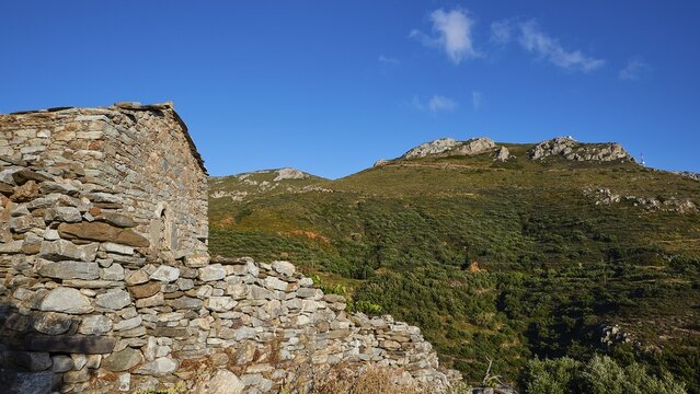 An old stone wall in front of a hilly landscape under a clear sky, Mani Peninsula, Peloponnese, Greece