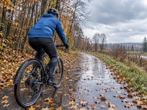 Un ciclista navega por un sendero en oto&ntilde;o con hojas ca&iacute;das en el suelo y un cielo nublado