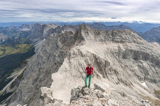 Woman standing on rocks and looking into the camera, view from Birkkarspitze, Karwendeltal, Tyrol, Austria