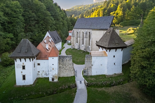 Elevated view of the historic Žiče Charterhouse (Žička kartuzija) monastery complex surrounded by lush forested hills near Slovenske Konjice, Slovenia