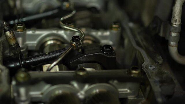 An opened cylinder head of an internal combustion engine exposes camshafts, a fuel line, and injector clamps under repair.