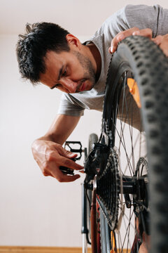 Close-up vertical shot of person engaged in DIY bicycle maintenance at home. Focused handyman tuning bike transmission. Hobby and active lifestyle concept.