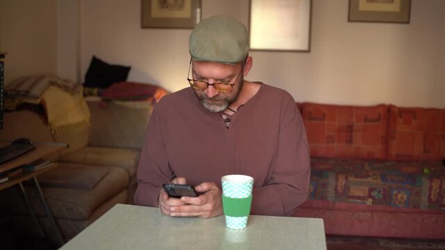 Handsome man at home typing messages on a smartphone