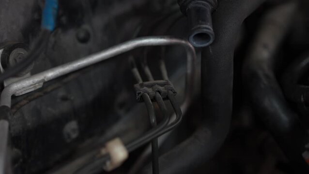 A close-up view shows three metallic brake or fuel lines secured with a plastic organizer clip along a car firewall partition.