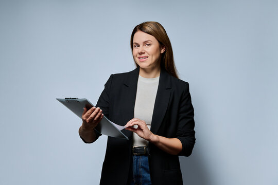 Female teacher holding clipboard and looking at camera studio portrait