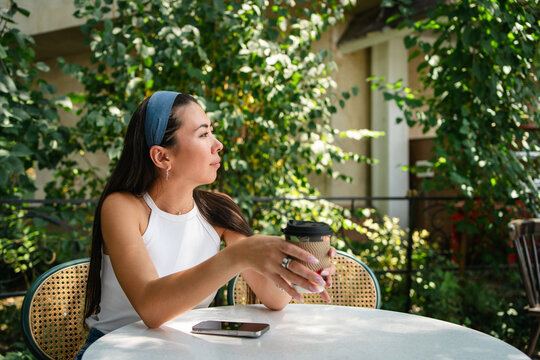 Young student relaxes with coffee at urban cafe terrace