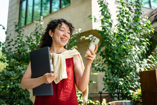 Smiling student use smartphone outside university building