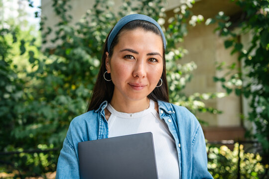 Female student with laptop in urban garden portrait
