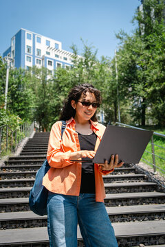 Student use laptop on urban stairway in summer