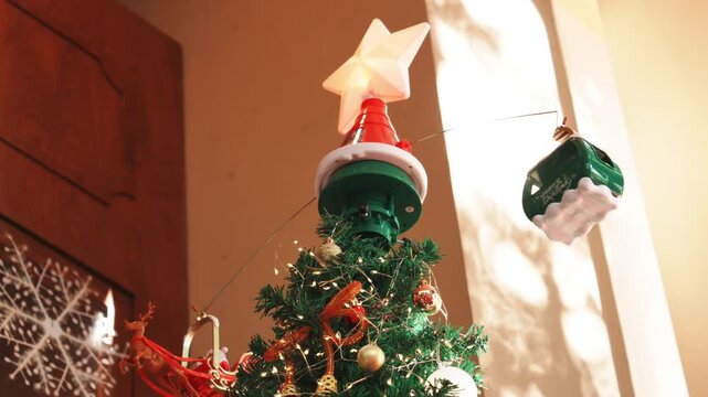 Star tree topper on Christmas tree with rotating Santa sleigh and cable car ornaments