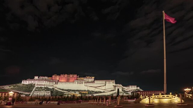 Potala Palace illuminated at night in Lhasa with Chinese national flag waving on flagpole
