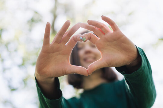 Woman form heart shape with hands in forest