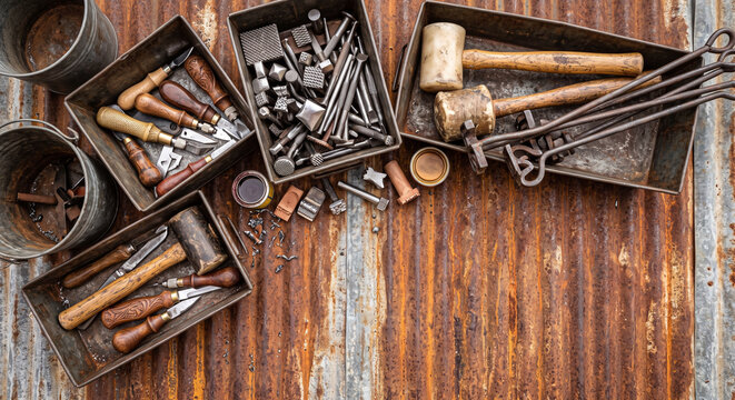 Cinematic overhead lay of Western leather carving tools on rusted steel