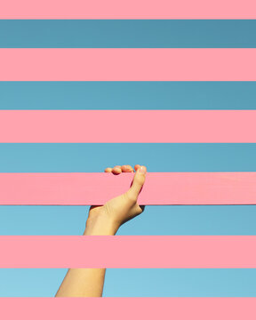 Hand emerge through pink strip against blue background