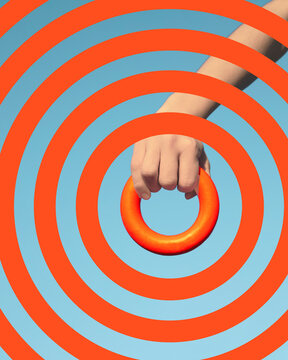 Hand holding orange ring within concentric circle pattern