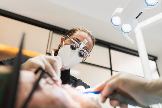 Dentist using loupes performing oral treatment on patient