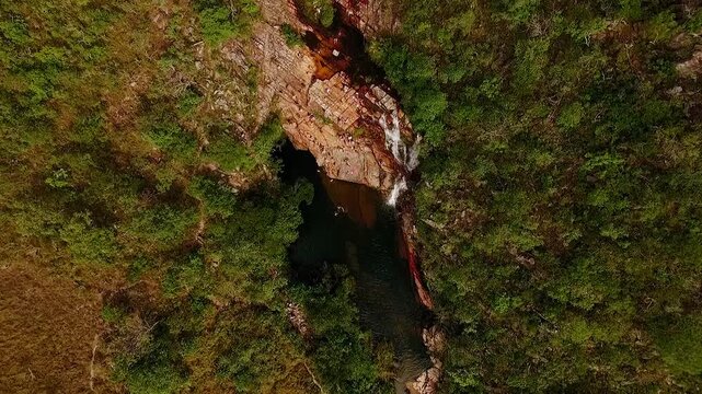 Almecegas II waterfall drops through a narrow quartzite gorge surrounded by Cerrado vegetation at Fazenda Sao Bento near Alto Paraiso de Goias, drone descent
