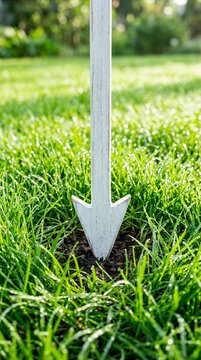 White Arrow Marker Stuck in Green Grass Lawn.