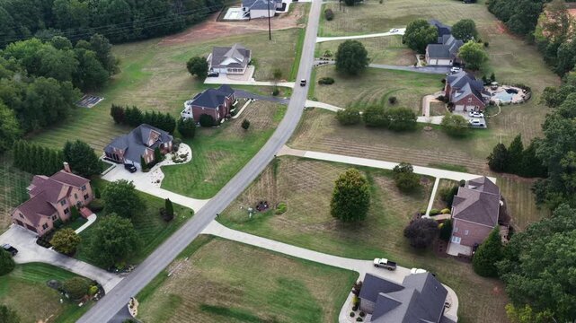 Large brick homes on generous lots line a quiet curving street with private pools and long driveways in a Forest, Virginia neighborhood. Aerial view