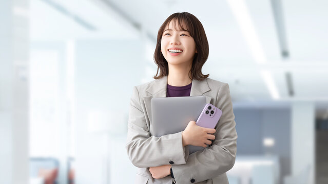 パソコンとスマートフォンを持つ笑顔の女性・ビジネスウーマン