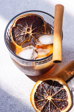 Spiced coffee cocktail with ice, cinnamon stick and orange slice