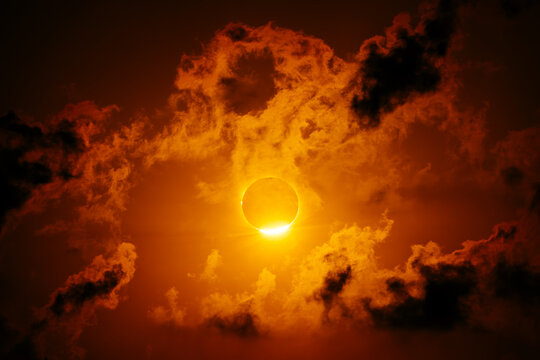 Solar eclipse with fiery clouds and glowing sun corona