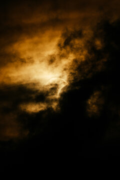 Partial solar eclipse behind dramatic golden storm cloud