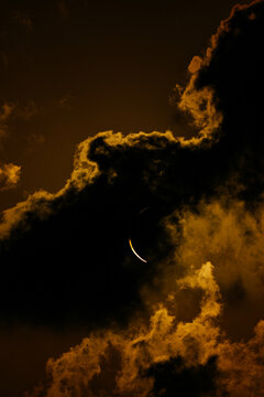 Eclipse crescent behind dramatic golden cloudscape