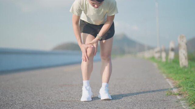 Young adult female runner with knee pain from ACL injury or patellofemoral syndrome. woman having joint ache, ligament tear or patellar tendinitis during running. Sports medical and healthcare concept