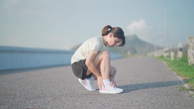 Young adult woman suffering from acute ankle pain during running workout. Female runner holding her leg due to sports injuries, ankle sprains or achilles tendonitis. Medical and healthcare concept