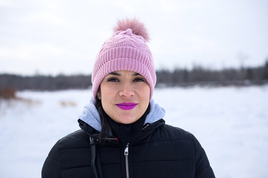 Serene woman in pink beanie against snowy winter landscape