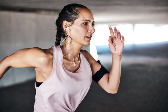 Running, exercise and woman with earphones for cardio training with sweat, body health or wellness. Female person, workout routine and commitment to intense fitness, underground or music for stamina