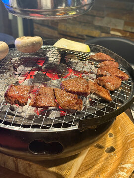 Delicious Korean BBQ meat grilling on a charcoal brazier net grill closeup