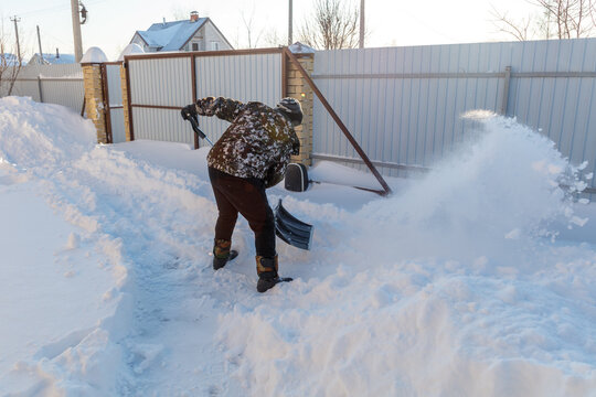 Person shovels snow from a yard path