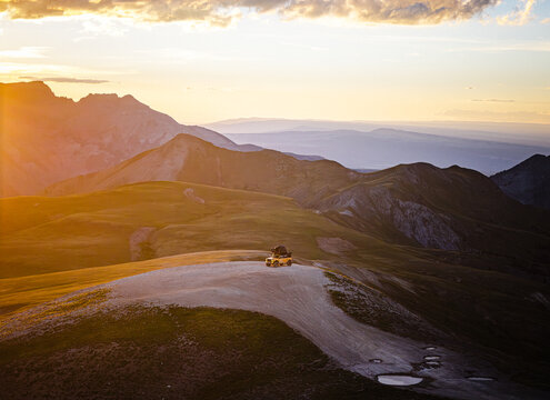 Off road vehicle on a scenic mountain summit at sunset