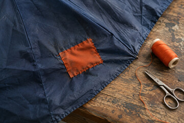Orange Fabric Patch Stitched onto a Faded Blue Umbrella